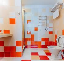 Imagine a beautifully designed bathroom featuring a stylish mix of vibrant red and crisp white tiles, along with a comfortable, efficient standard toilet for user convenience photo
