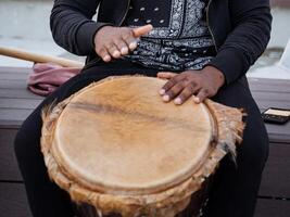 Experience the Rhythmic Beats A CloseUp Perspective of Hands Skillfully Playing a Traditional Drum with vibrant community energy photo