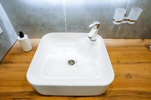 The white sink pairs beautifully with the wooden bathroom counter, creating a cohesive look that enhances the rooms appeal aesthetically and blends seamlessly with the surroundings photo