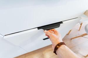 A person is performing a gesture on a white desk as they press a button photo