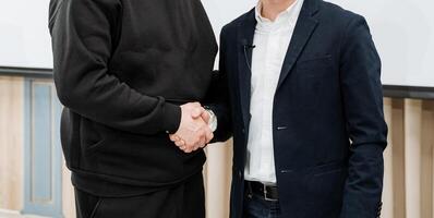 Two men are engaging in a handshake, which is a wellknown gesture of greeting that signifies their friendly interaction and demonstrates mutual respect and understanding between them photo
