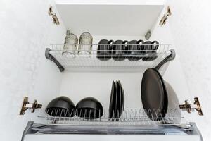 A dish rack that is filled with various items such as plates, cups, and pans, making it a useful kitchen accessory for organizing and drying dishes efficiently after washing them photo