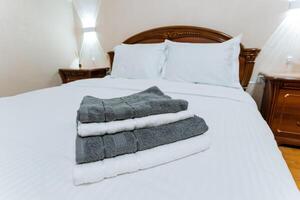 A neatly made bed, beautifully adorned with crisp white sheets, and a fluffy stack of towels placed perfectly on top, creates a fresh and inviting atmosphere throughout the room photo