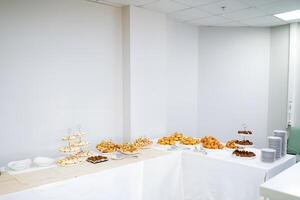 The room features a buffet table filled with a variety of food items, likely set up for an event. The decor includes wooden flooring, a rectangular table, and a ceiling above photo