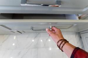 A person is in the process of opening a drawer located in a kitchen photo
