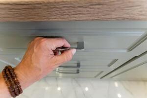 A person is using a screwdriver to open a drawer in their home photo