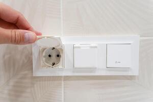 An individual is plugging a light switch into a standard electrical outlet photo