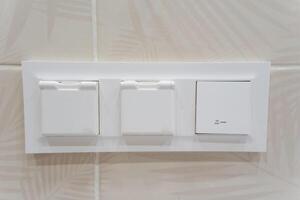Close up image of a white light switch on a tiled wall photo