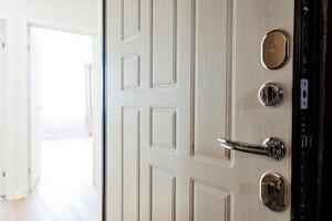 White door with chrome handle open to hallway in building photo