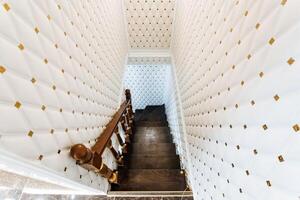 A beautifully designed staircase featuring a wooden railing alongside a pristine white wall that is decorated with stylish gold polka dots, creating an appealing visual balance photo