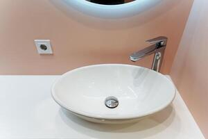The bathroom sink is beautifully designed with a sleek faucet and accompanied by a stylish mirror positioned above it, which together create a serene and elegant atmosphere in the space photo