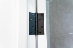 Detailed CloseUp View of a Stylish Black Door Hinge Positioned on a Contemporary Glass Door, showcasing its sleek design and function photo