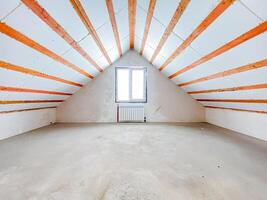 An old, empty attic space featuring exposed wooden beams and a single window that allows light to filter through, creating a tranquil ambiance in the rooms serene atmosphere photo