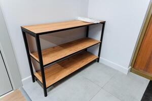 A beautifully crafted wooden shoe rack is placed elegantly in a hallway, right next to the entrance door, providing both outstanding functionality and a stylish touch to the entire area photo