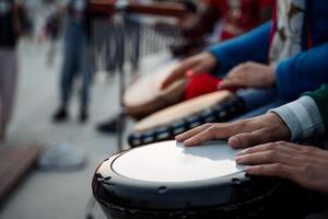 A group of hands skillfully playing drums in a vibrant outdoor setting, creating a lively atmosphere filled with music and rhythm photo