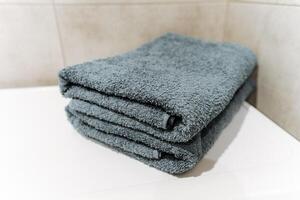 Grey linens stack on white counter, adding comfort and fashion to the room photo