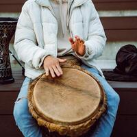 A person is playing a traditional drum in an outdoor setting, creating a vibrant atmosphere filled with cultural music and rhythmic sounds photo
