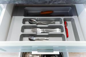 In the kitchen, one particular drawer is filled to the brim with a variety of silverware, and interestingly, a bright red pen is nestled among the other assorted utensils photo