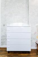 Wood chest of drawers on wheels by crib in nursery photo