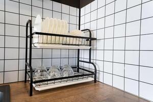 In the kitchen, there is a dish rack that holds various plates and glasses neatly organized on it, showcasing an arrangement essential for maintaining a tidy and functional space photo