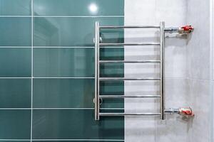 A towel rack is currently and prominently hanging on a tiled wall within a bathroom space, providing a practical and convenient place for drying and hanging towels after use photo