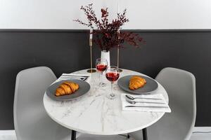 Experience an Elegant Dining Table Setting featuring delicious Croissants and fine Wine for a perfectly Cozy Meal to enjoy together photo