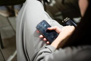 A woman is sitting comfortably on a chair while holding a cell phone in her hand, seemingly engaged in a conversation or activity using her communication device with focus and interest photo