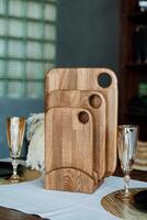Three beautifully crafted wooden cutting boards are thoughtfully stacked on top of one another upon a sturdy table, showcasing their unique designs and rich wood grain patterns photo