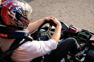A man who is wearing a protective helmet is driving a fast gokart and is skillfully showcasing his impressive abilities while fully enjoying the exhilarating thrill of racing photo