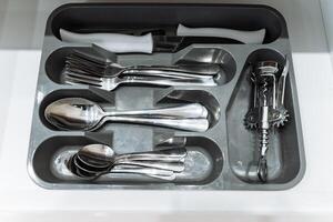 A tray designed specifically for silverware is completely filled with various types of silverware and utensils for dining and serving food and are essential elements of table setting photo