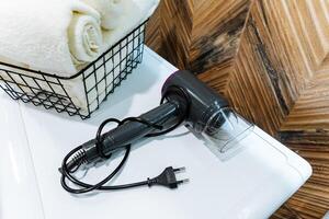 A hair dryer is positioned thoughtfully on a countertop, positioned adjacent to a basket filled with neatly organized towels, which together create a clean, tidy, and practical environment photo