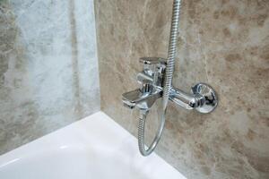 A welldesigned bathroom features a spacious bathtub with an overhead shower head, providing users the flexibility to enjoy both bathing and showering at their convenience photo