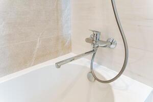 In the bathroom, there exists a bathtub that comes equipped with a shower head firmly fixed to it, ensuring a practical and enjoyable bathing experience for all individuals using the space photo