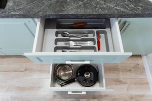 Inside a kitchen drawer, there is a diverse collection that includes various pots, pans, and cooking utensils all organized together for convenient access when preparing meals photo