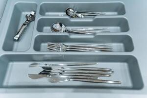 The drawer specifically designed for silverware is packed with an assortment of silverware items, which includes various types of knives, forks, spoons, and tongs for every dining occasion photo