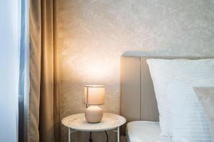 The elegantly furnished bedroom boasts a comfy bed, a stylish nightstand, a warm lamp that provides soft lighting, and a bright window, all contributing to a cozy and inviting atmosphere photo