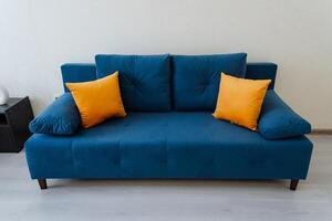 In a cozy living room, there is a striking blue couch adorned with vibrant yellow pillows, creating a cheerful and inviting atmosphere that is perfect for relaxation and comfort photo