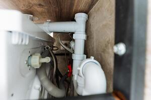 This image shows a detailed closeup of a pipe located under a kitchen sink, highlighting various plumbing components and connections essential for proper kitchen functionality photo