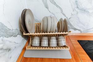 A rustic wooden dish rack is filled with an assortment of plates and cups neatly arranged in a cozy kitchen setting, creating an inviting atmosphere for meal preparation photo