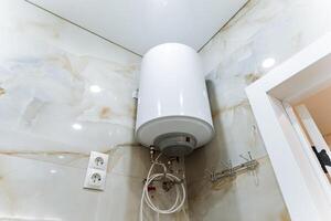 In the bathroom, look up and youll notice a white water heater that is securely mounted from the ceiling, providing essential access to hot water whenever it is needed for use photo
