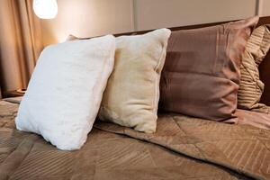 In the cozy room, there are three incredibly soft and fluffy pillows that rest on top of a beautifully and neatly made bed, contributing to a warm, comfortable, and inviting atmosphere photo