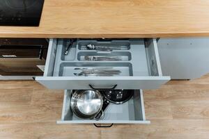 Inside a kitchen drawer, there are various pots and pans organized neatly, ready for use in meal preparation and cooking. This drawer is an essential part of kitchen storage photo