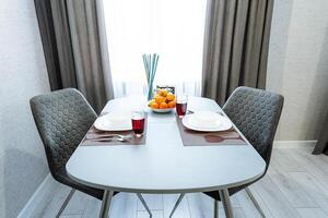 In the dining room, there is a beautifully set table accompanied by two stylish chairs, with plates neatly arranged on the surface, creating a welcoming atmosphere for meals photo
