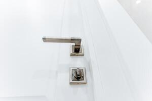 Grey handle on white bathroom door, locking mechanism, bottom view of door handle. photo