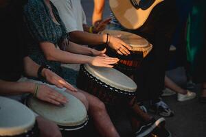 A lively group of people are enthusiastically playing drums while a talented man skillfully plays a guitar, creating an energetic atmosphere filled with delightful music and entertainment photo