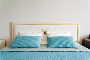 Aqua bedding and pillows on wood bed frame in rectangular bedroom fixture photo