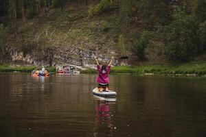 A woman is currently standing on a paddle board while enjoying her time in the water, taking in the surrounding natural scenery and the beauty of the landscape around her photo