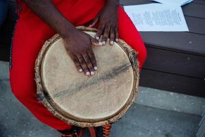 Hands Skillfully Positioned on a Drum Captivating Rhythm in Stunning Red Attire, Evoking Energy and Emotion in a Joyous Celebration photo