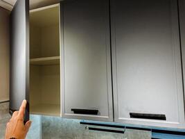 A person is currently in the process of opening a cabinet door that is situated within a kitchen area, where various items may be stored or arranged for easy accessibility photo