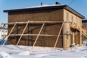 A house is being built on a snowy slope with scaffolding around it photo